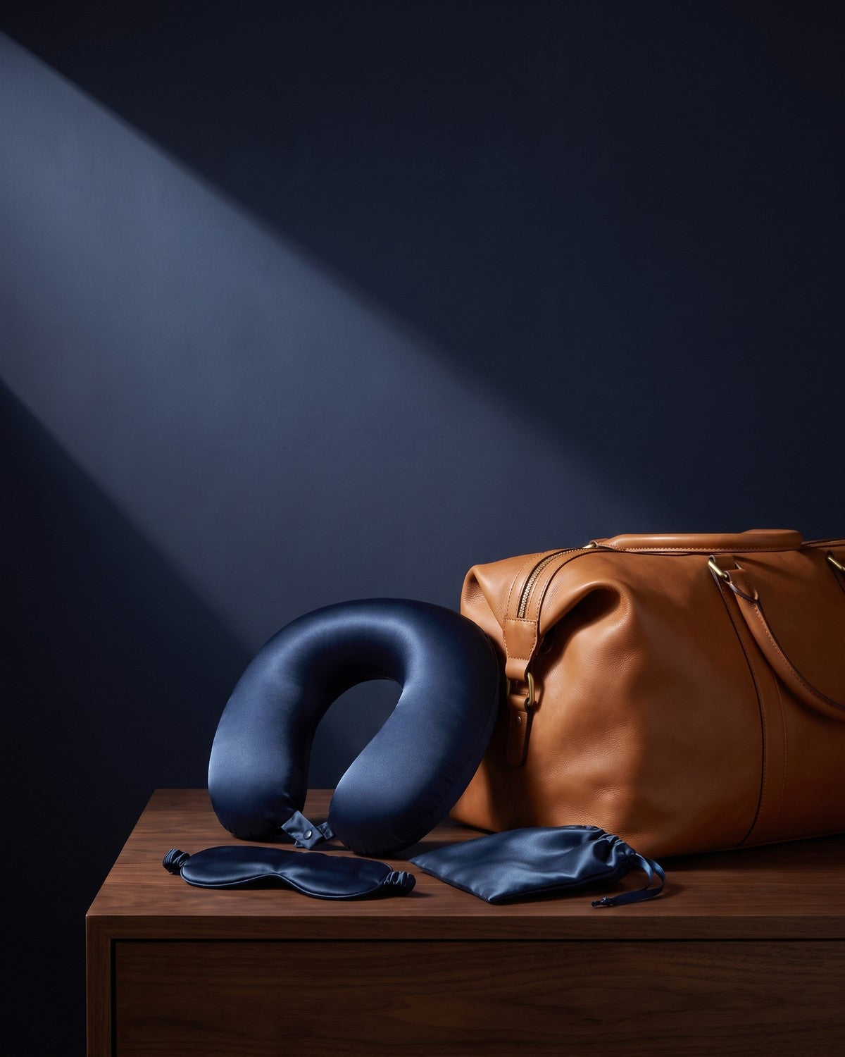 KINT silk travel set beside a leather weekend bag