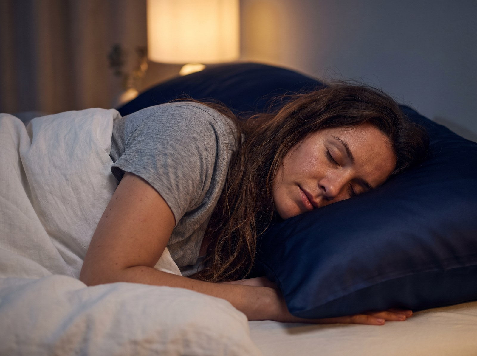Woman sleeping peacefully on a navy KINT mulberry silk pillowcase