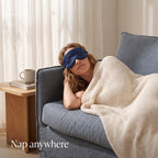 Woman napping on a sofa wearing the navy KINT classic silk sleep mask
