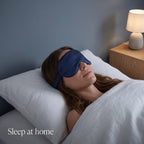 Woman asleep in bed wearing the navy KINT classic silk sleep mask