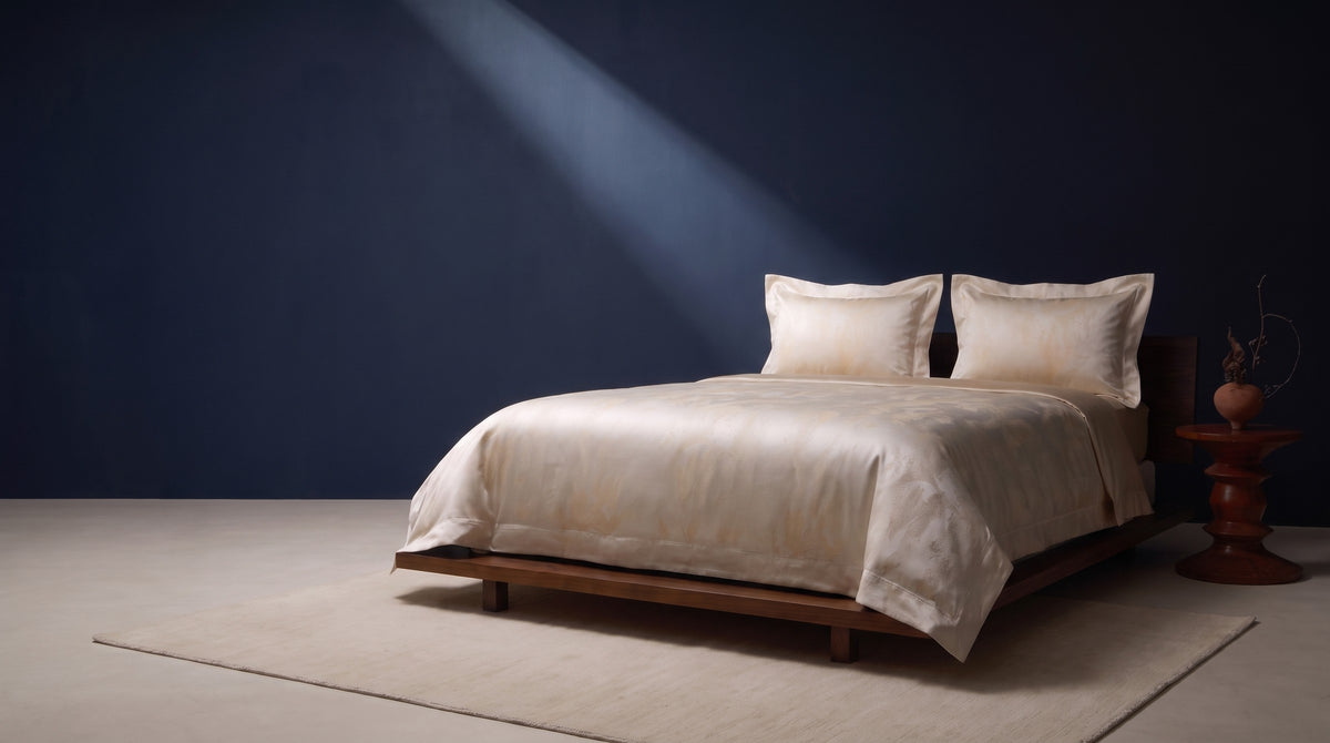 Woman sleeping peacefully on a slate blue silk pillowcase under navy silk bedding