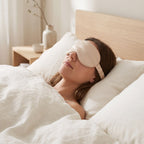 Woman asleep in a bright Scandinavian bedroom wearing the KINT silk sleep mask