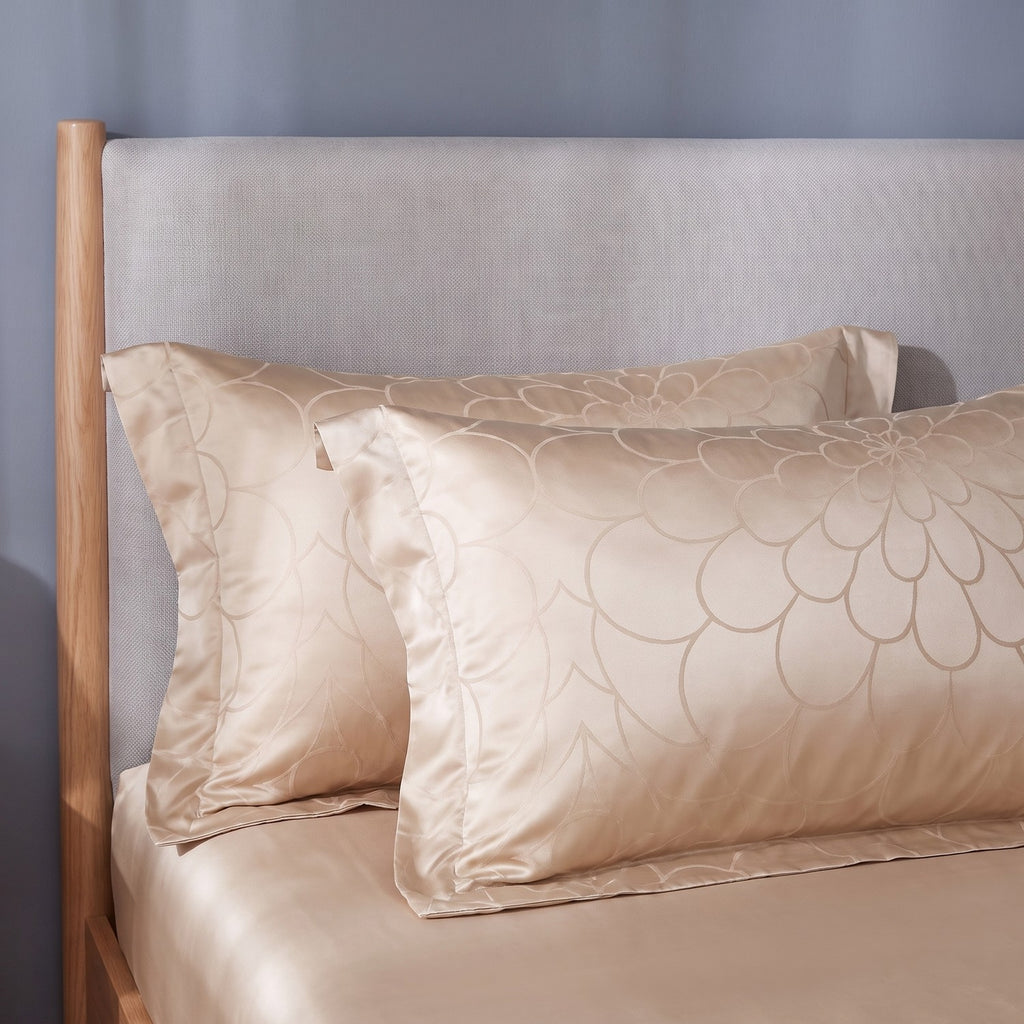 Two jacquard pillowcases with a satin flange border against a linen headboard