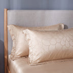 Two jacquard pillowcases with a satin flange border against a linen headboard