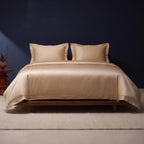 KINT silk and cotton satin bedding set in Light Gold on a low walnut bed against a navy wall