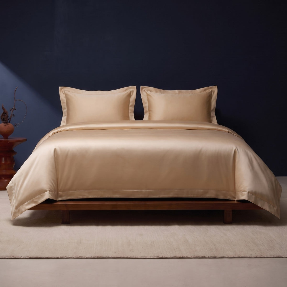 KINT silk and cotton satin bedding set in Light Gold on a low walnut bed against a navy wall