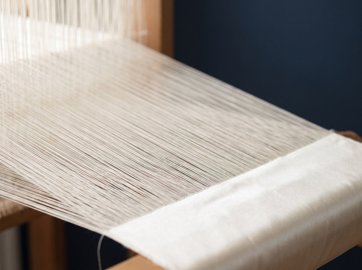 Fine silk threads on a loom forming woven silk fabric