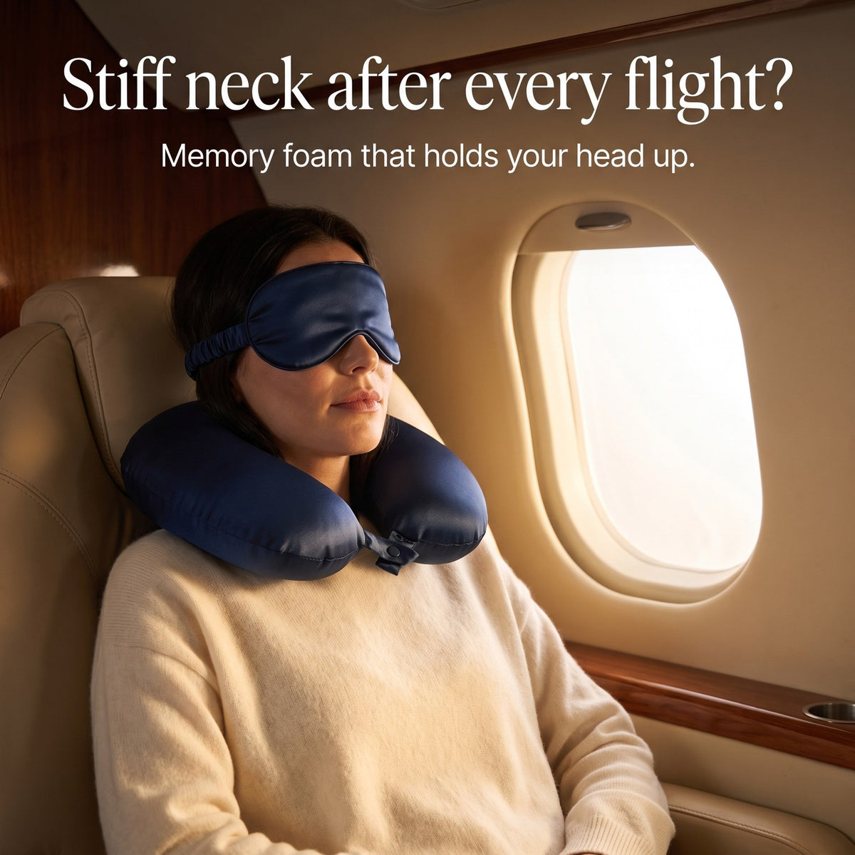 Woman asleep in an airplane window seat with the navy KINT silk neck pillow and sleep mask