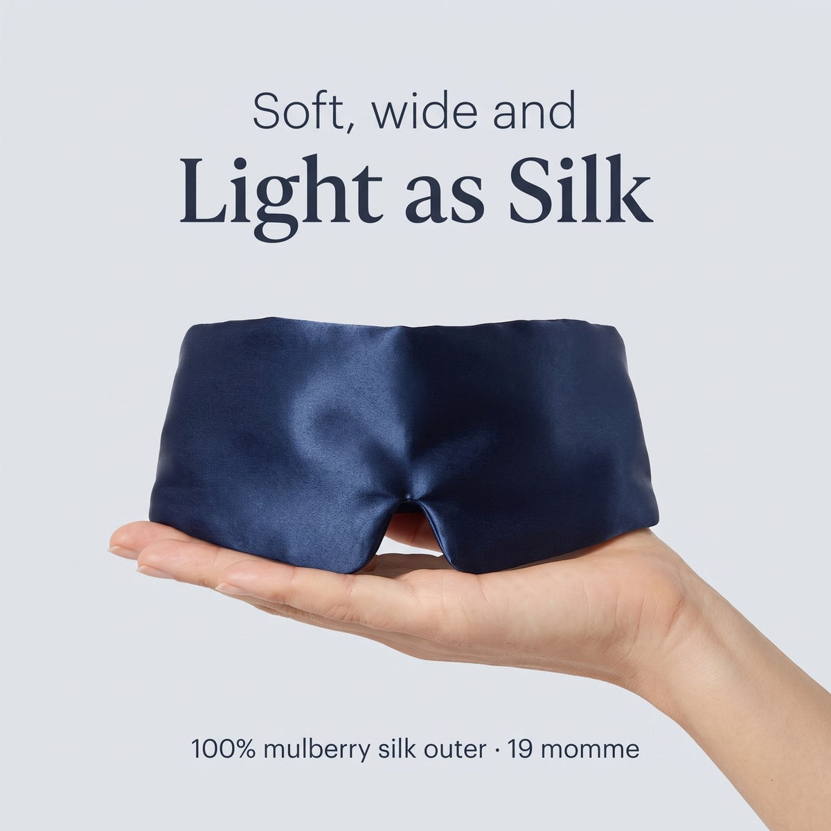 Hand holding the KINT silk wrap sleep mask in Navy, 100% mulberry silk outer