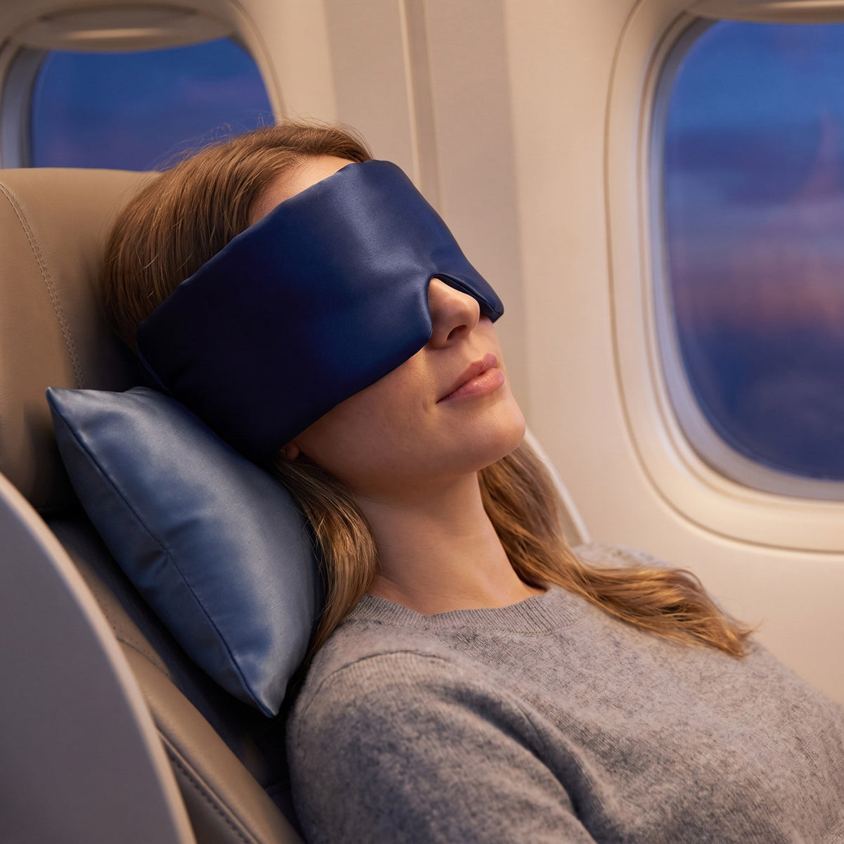 Woman resting on a plane wearing the KINT silk wrap sleep mask