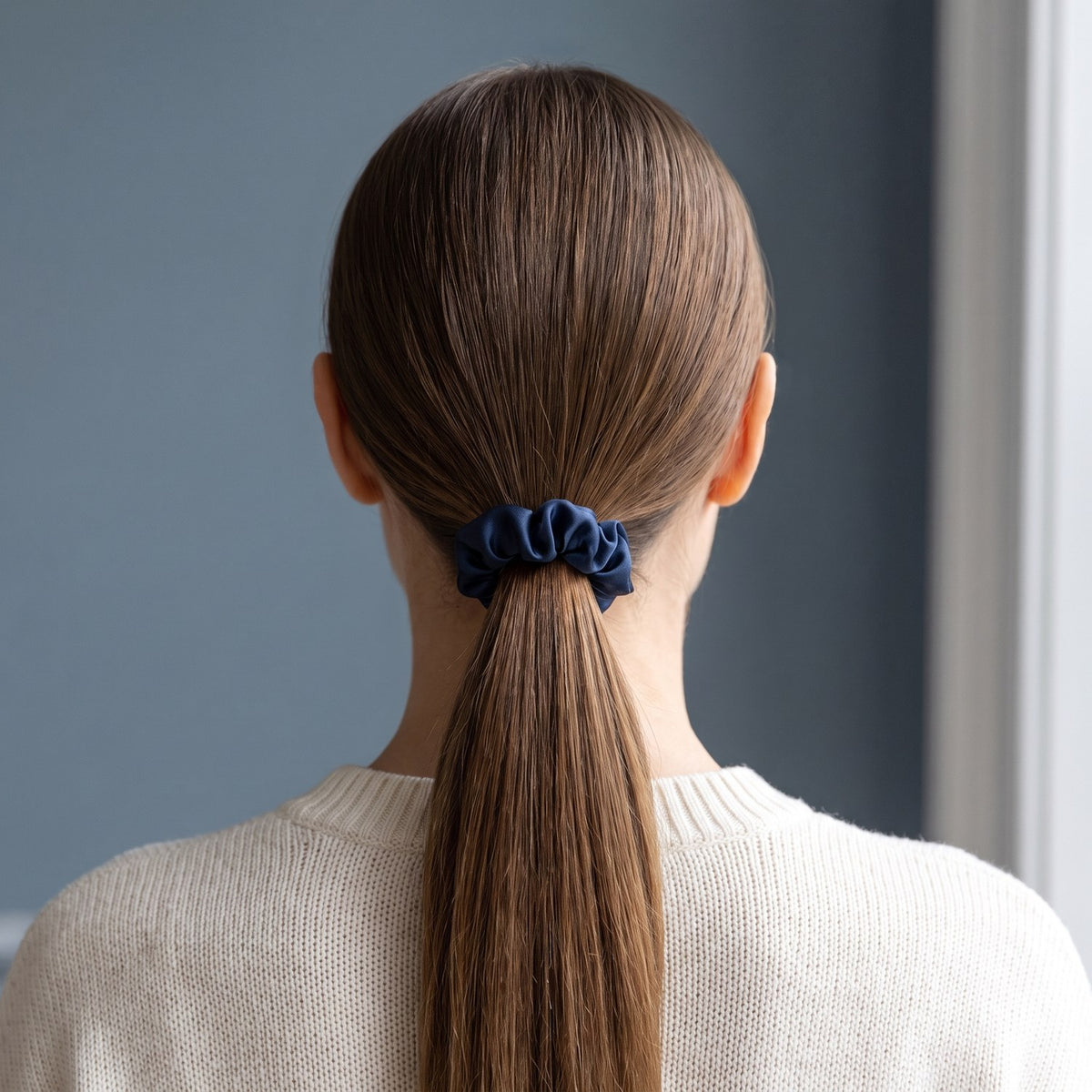 A low ponytail tied with the slim navy KINT silk scrunchie